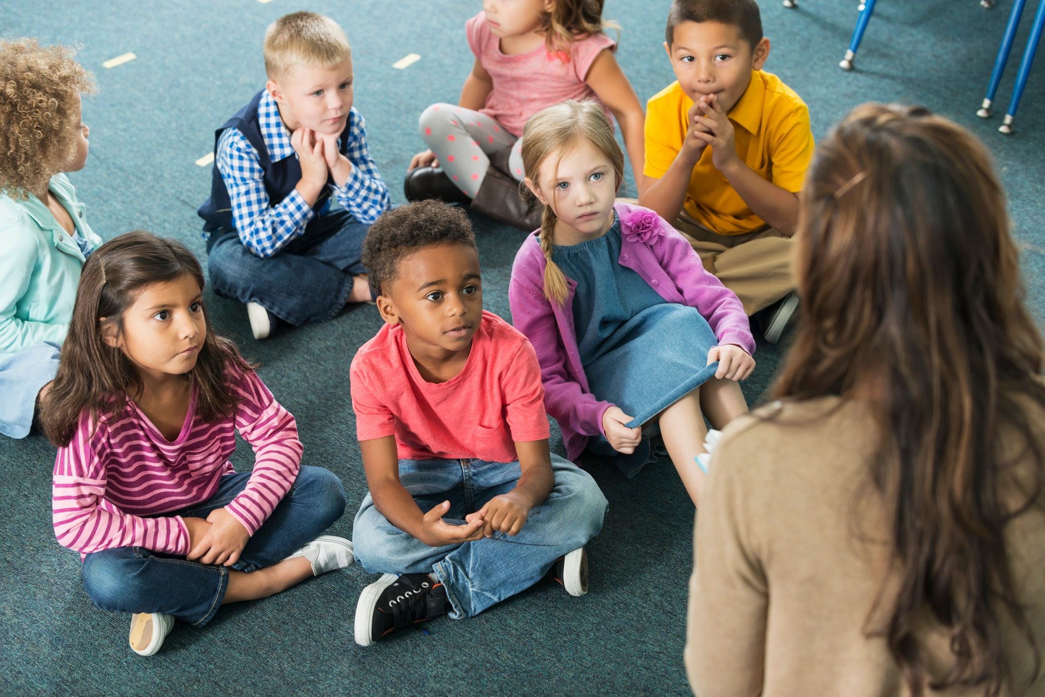 Kindergarten students listening to a teacher in a classroom